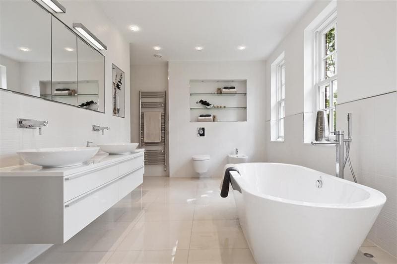 White bathroom with countertop basins, freestanding bath, toilet