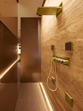 shower with gold and stone surfaces, gold bathroom design
