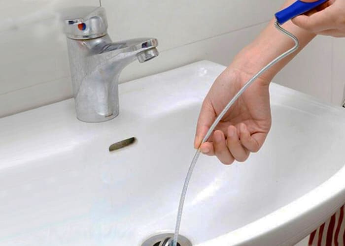 unblocking the sink with a plumbing snake 