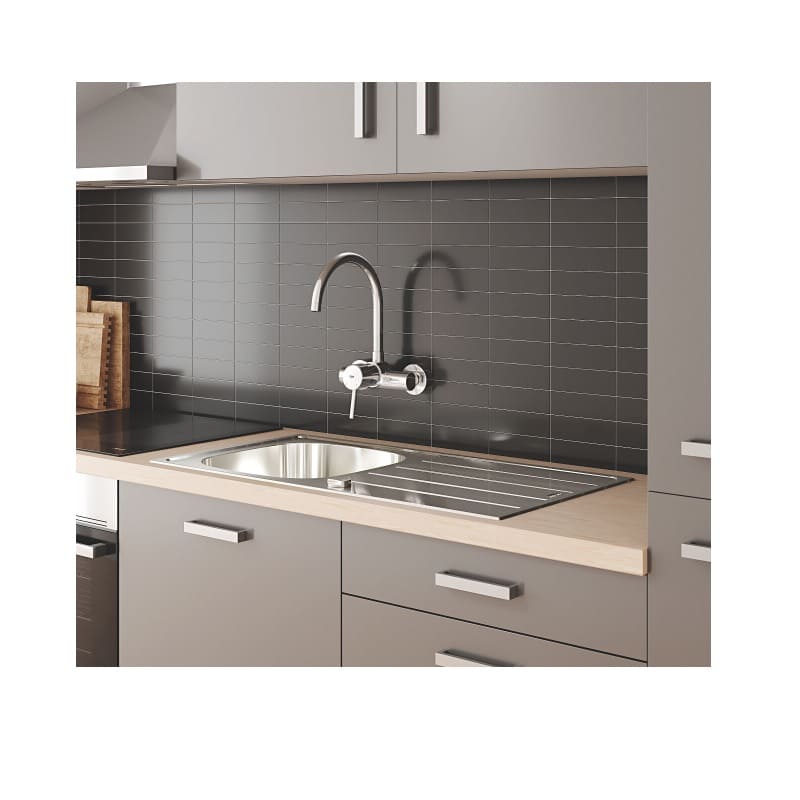 A kitchen tap mountend to the wall on a gray wall