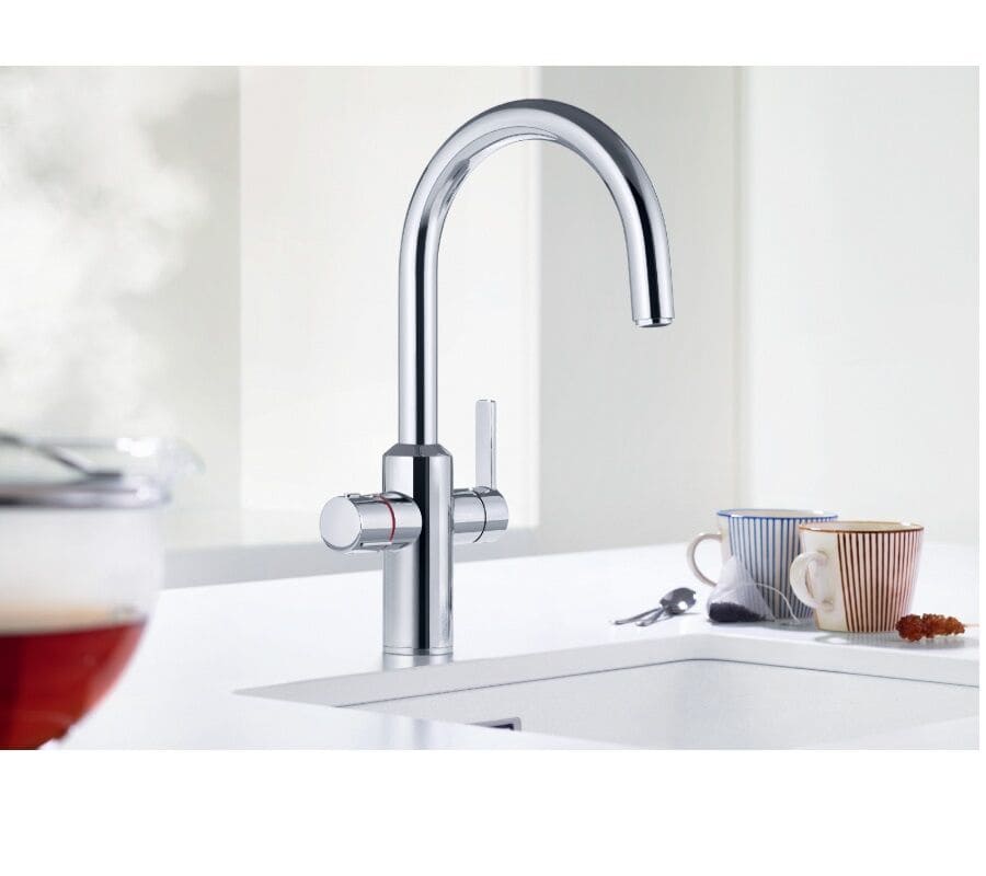 A silver kitchen tap with two levers in a white kitchen and two mugs